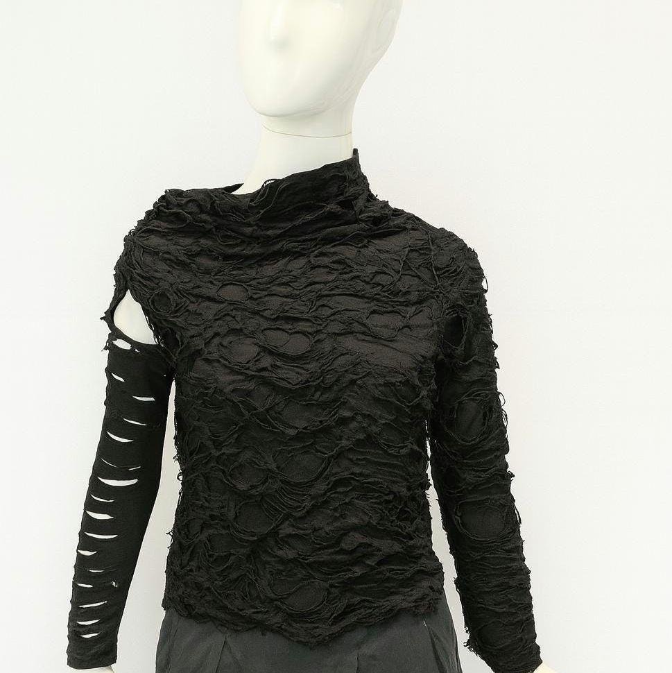 Afterrift Top — cyberpunk asymmetric black textured top with a slashed sleeve on a mannequin, framed just below the sleeve cuffs